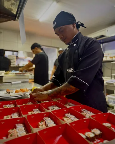 Sushiman montando os pedidos nas caixas da rede